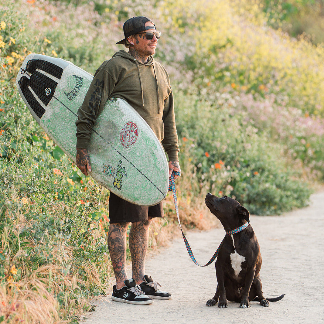 A surfer walking his dog with the Kuthro Azteca premium dog leash.